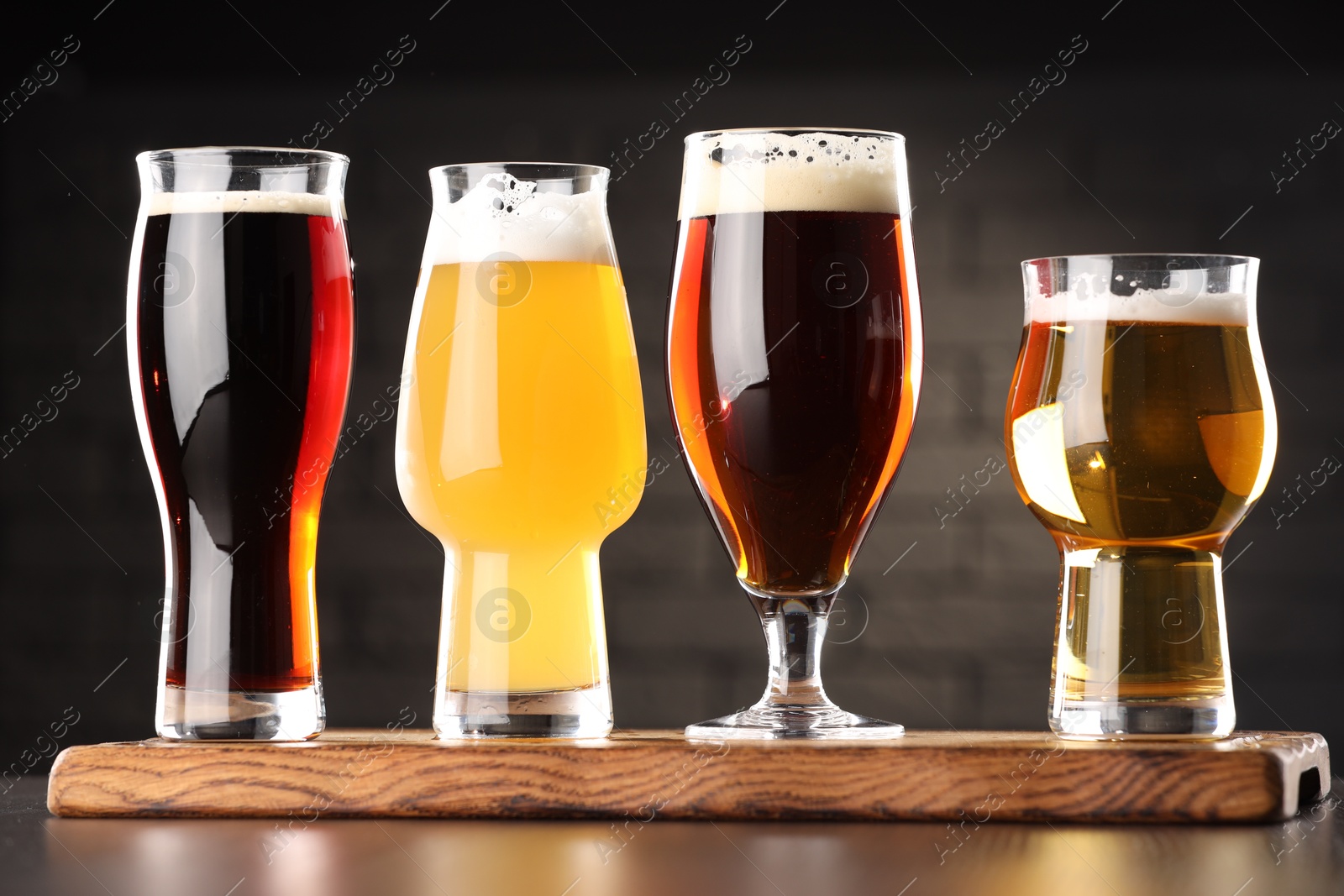 Photo of Glasses with different types of beer on wooden table in bar