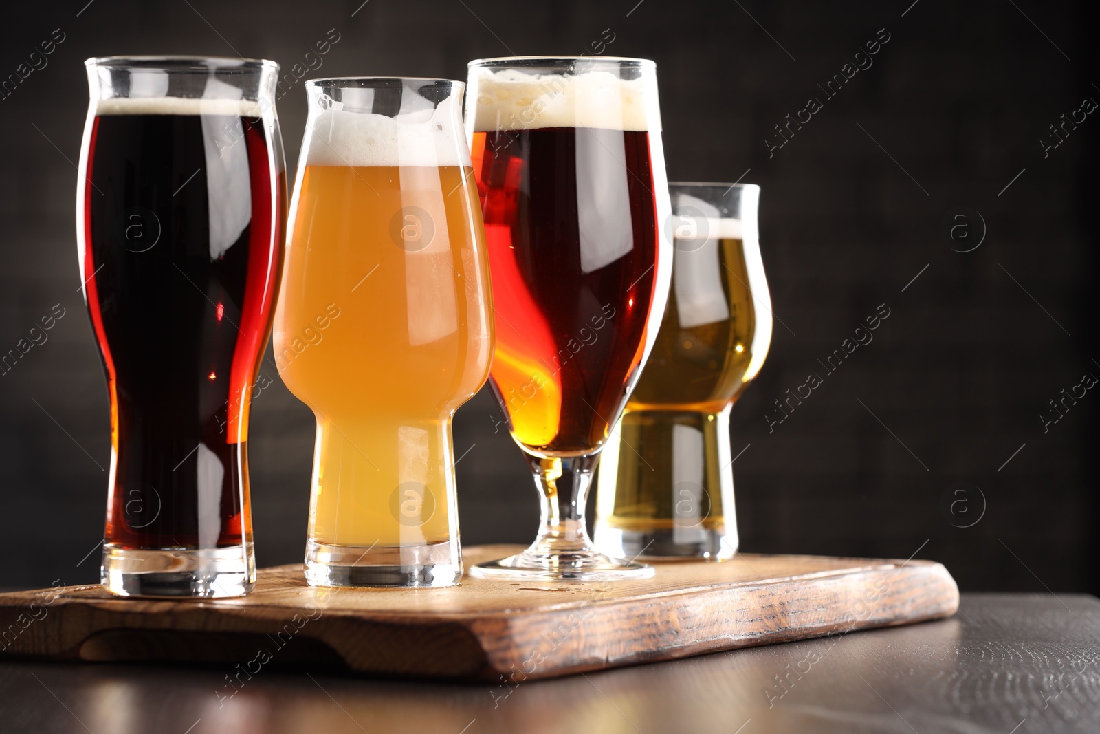 Photo of Glasses with different types of beer on wooden table in bar, closeup