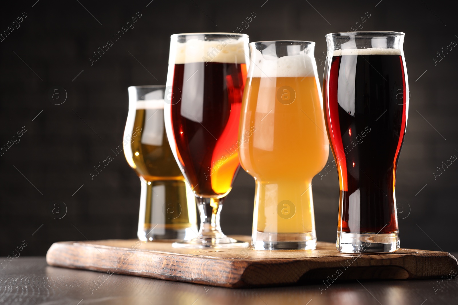 Photo of Glasses with different types of beer on wooden table in bar, closeup