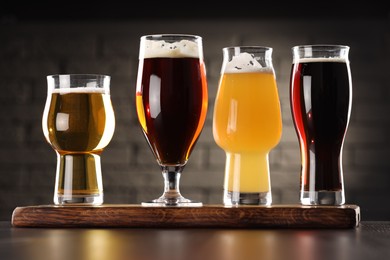 Photo of Glasses with different types of beer on wooden table in bar