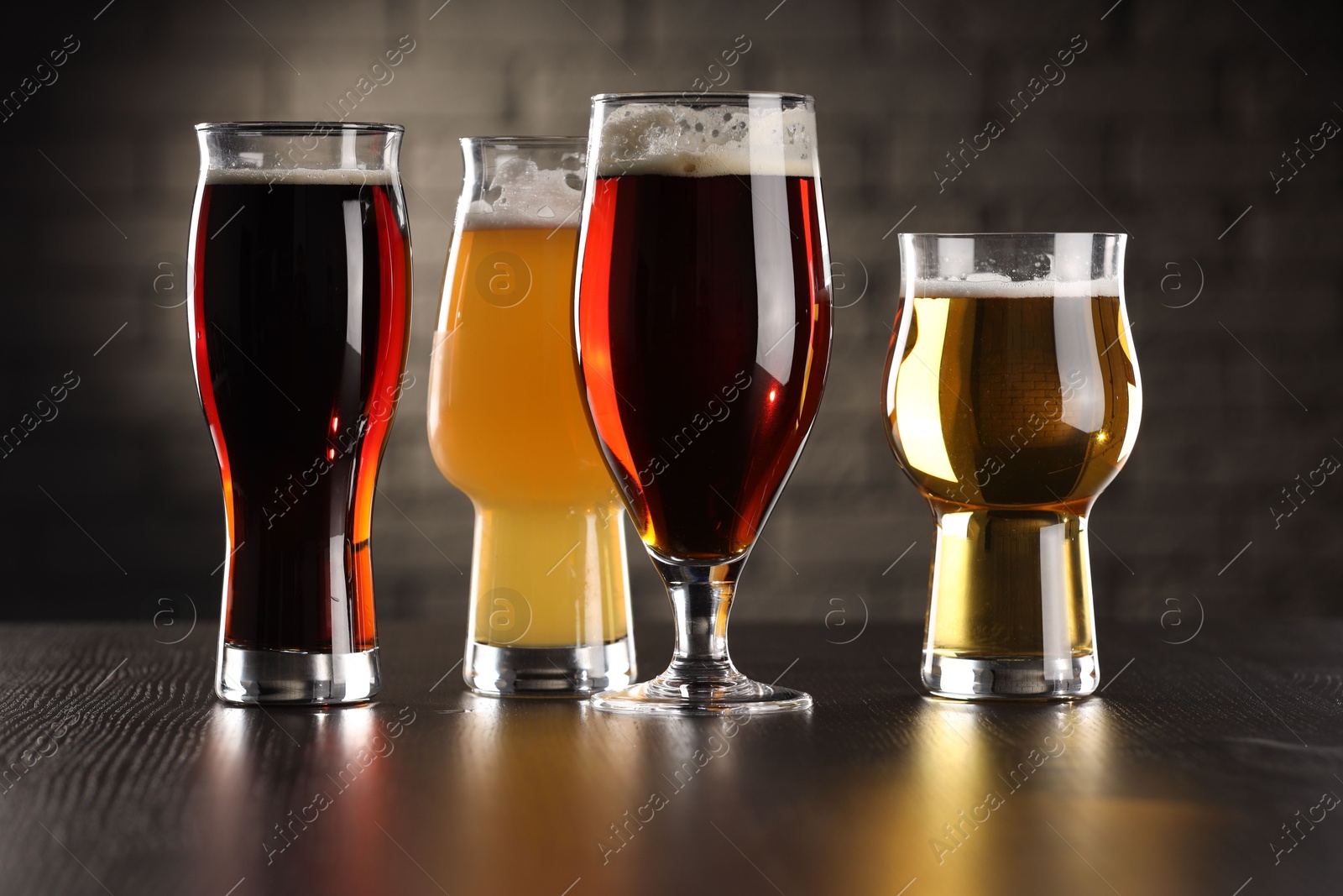 Photo of Glasses with different types of beer on wooden table in bar