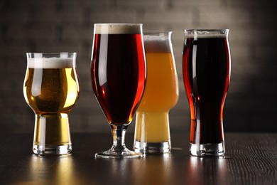 Photo of Glasses with different types of beer on wooden table in bar