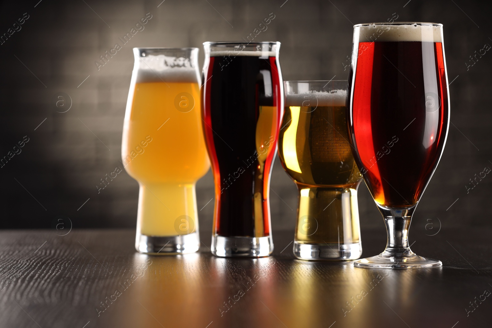 Photo of Glasses with different types of beer on wooden table in bar