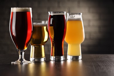 Photo of Glasses with different types of beer on wooden table in bar