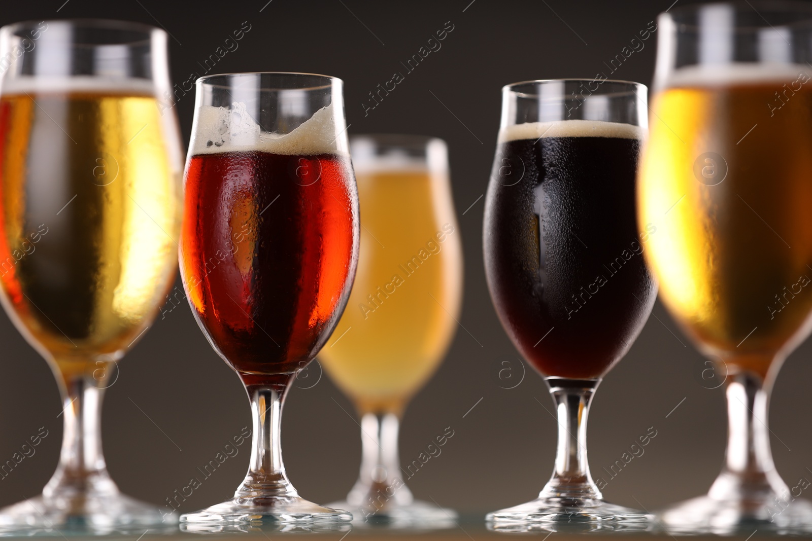 Photo of Glasses with different types of beer on grey background, closeup