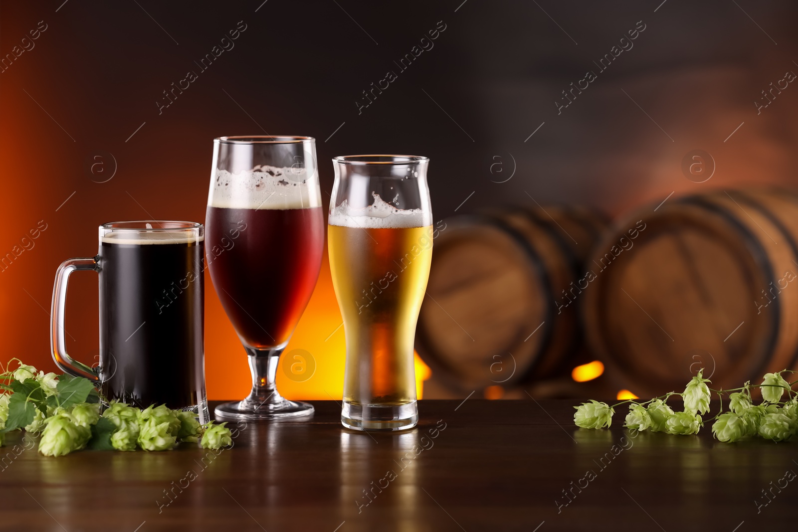 Photo of Glasses with different types of beer and fresh hops on wooden table in bar. Space for text