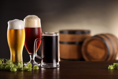 Photo of Glasses with different types of beer and fresh hops on wooden table in bar. Space for text