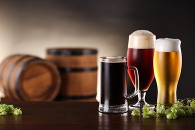 Photo of Glasses with different types of beer and fresh hops on wooden table in bar. Space for text