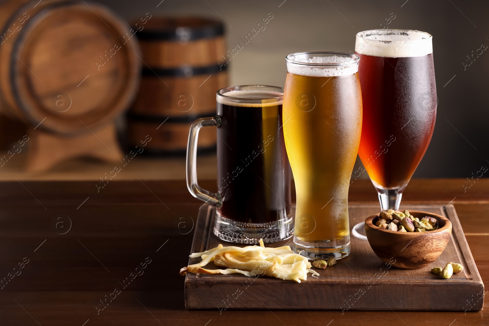 Photo of Glasses with different types of beer and snacks on wooden table in bar. Space for text