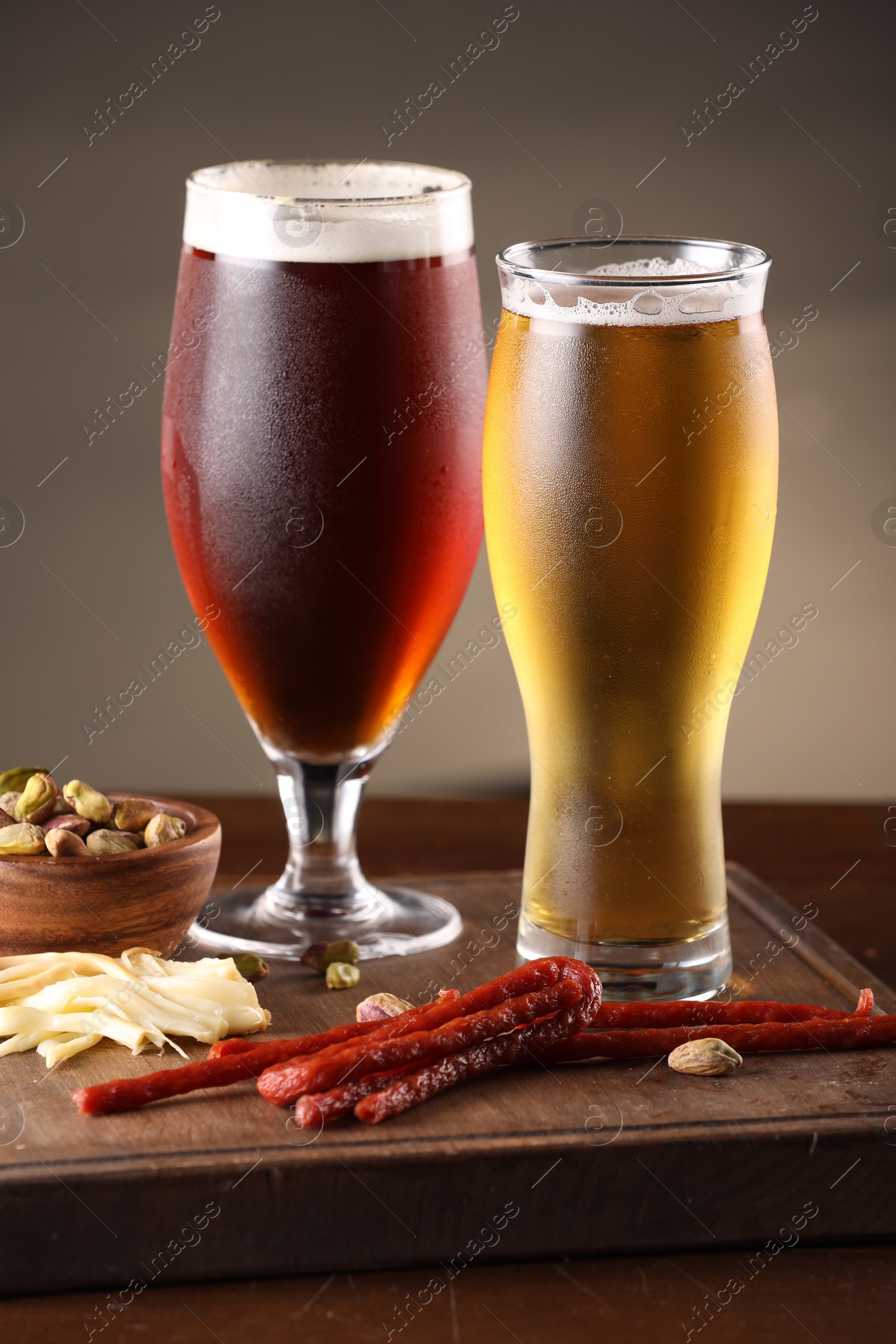 Photo of Glasses with different types of beer and snacks on wooden table, closeup