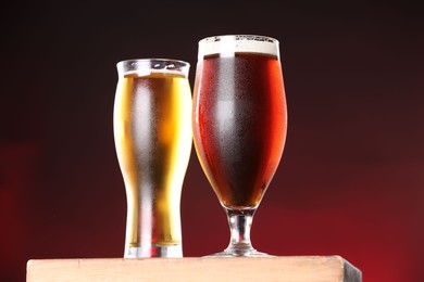 Photo of Glasses with different types of beer on board against dark background, closeup