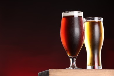 Photo of Glasses with different types of beer on board against dark background, closeup. Space for text