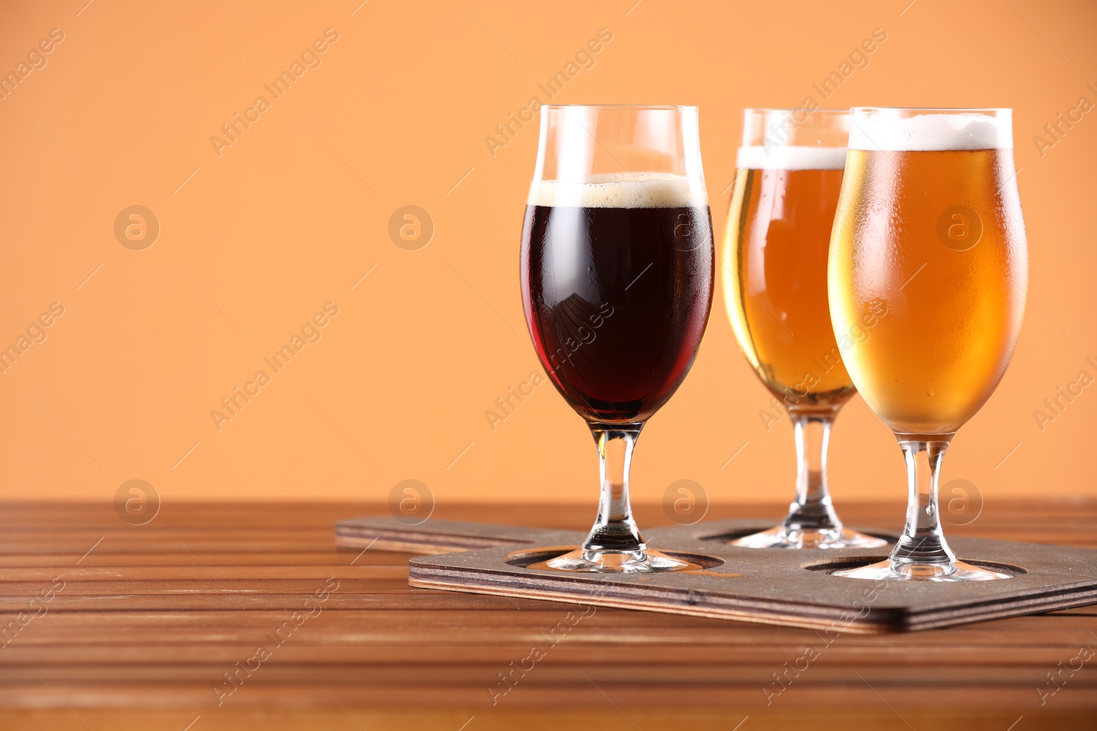 Photo of Glasses with different types of beer on wooden table. Space for text