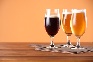 Photo of Glasses with different types of beer on wooden table. Space for text