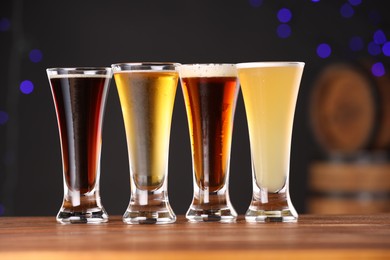 Photo of Glasses with different types of beer on wooden table against blue background, closeup