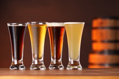 Photo of Glasses with different types of beer on wooden table in bar, closeup