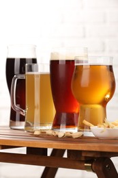 Photo of Glasses with different types of beer and snacks on wooden table