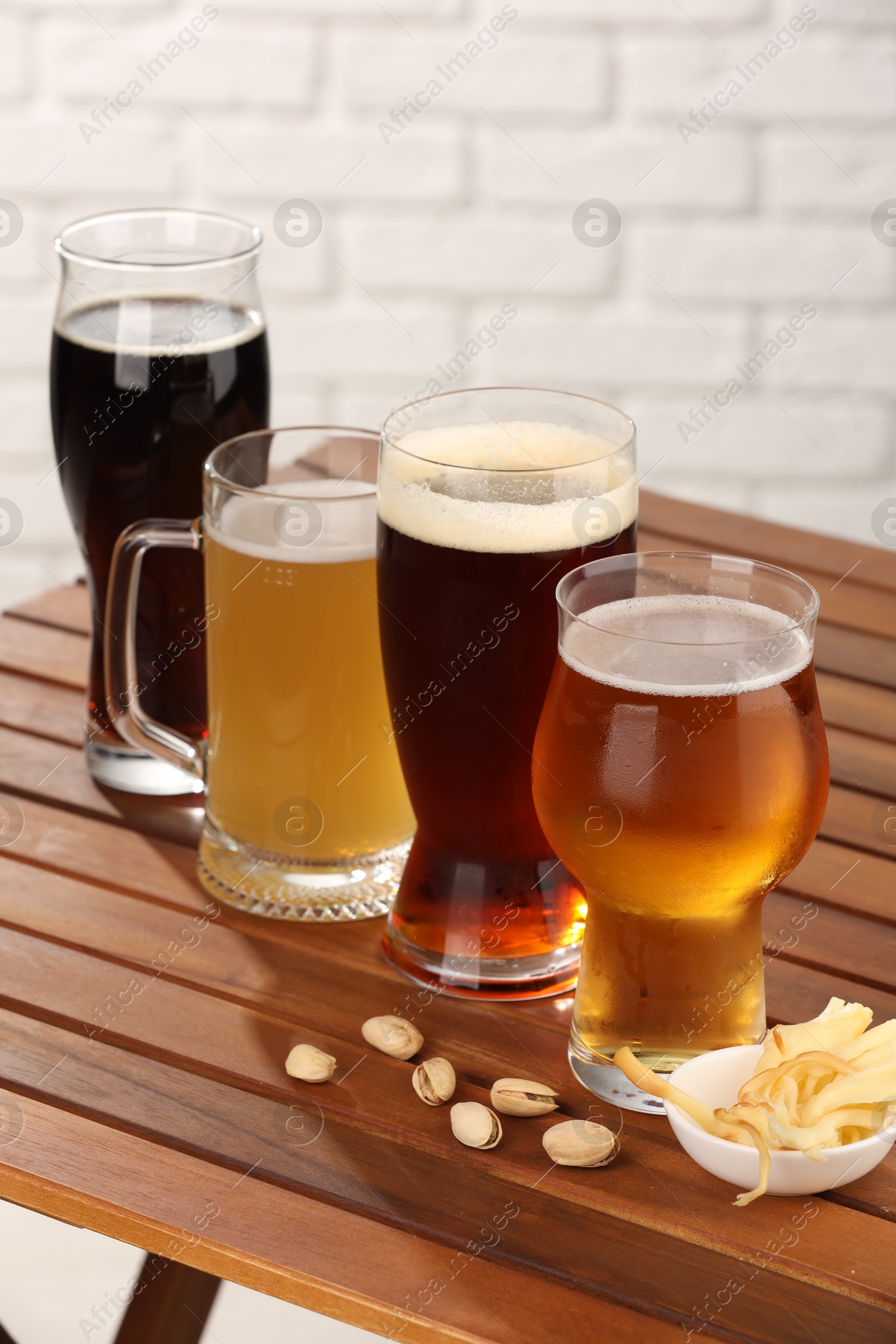 Photo of Glasses with different types of beer and snacks on wooden table