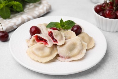 Traditional Ukrainian dumplings (varenyky) with cherries served on light table, closeup