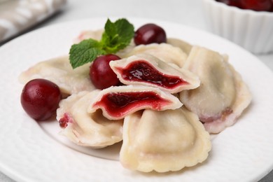 Traditional Ukrainian dumplings (varenyky) with cherries on light table, closeup