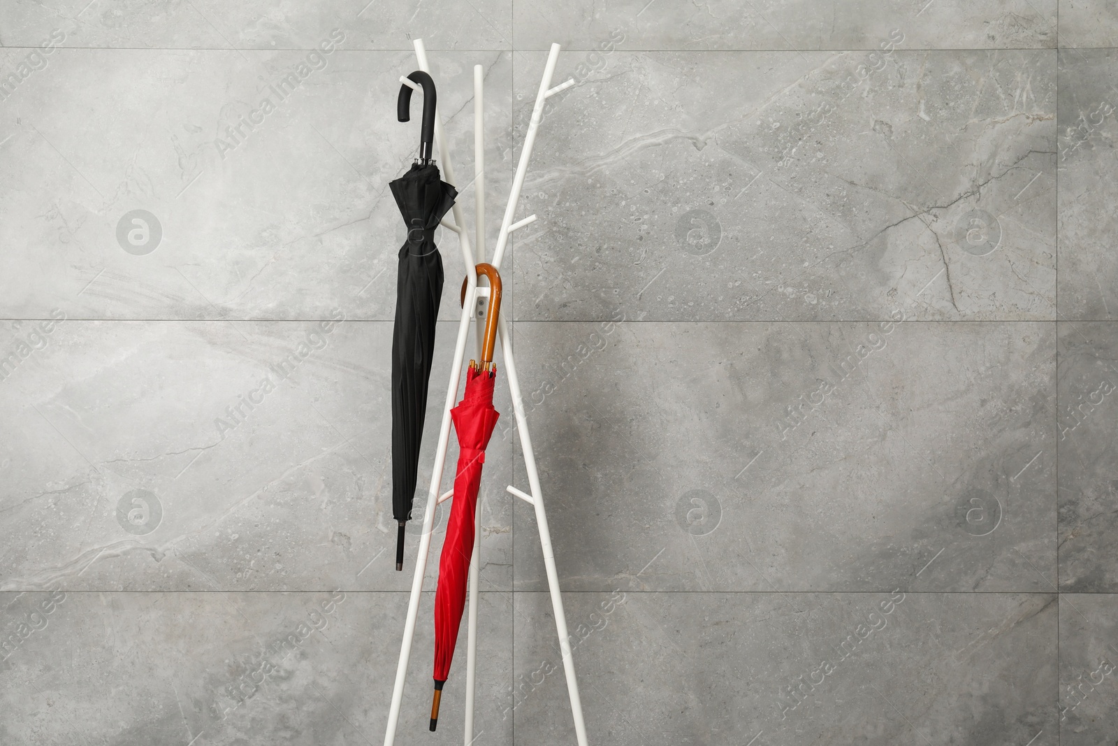 Photo of Colorful umbrellas on rack near gray marble wall