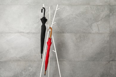 Colorful umbrellas on rack near gray marble wall