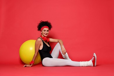 Aerobics. Happy woman with fitness ball on red background