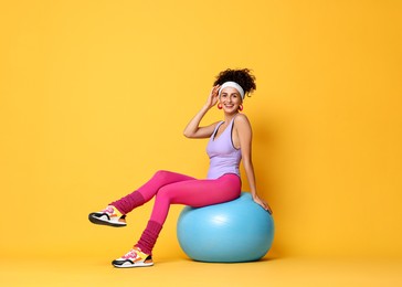 Aerobics. Woman with fitness ball on orange background