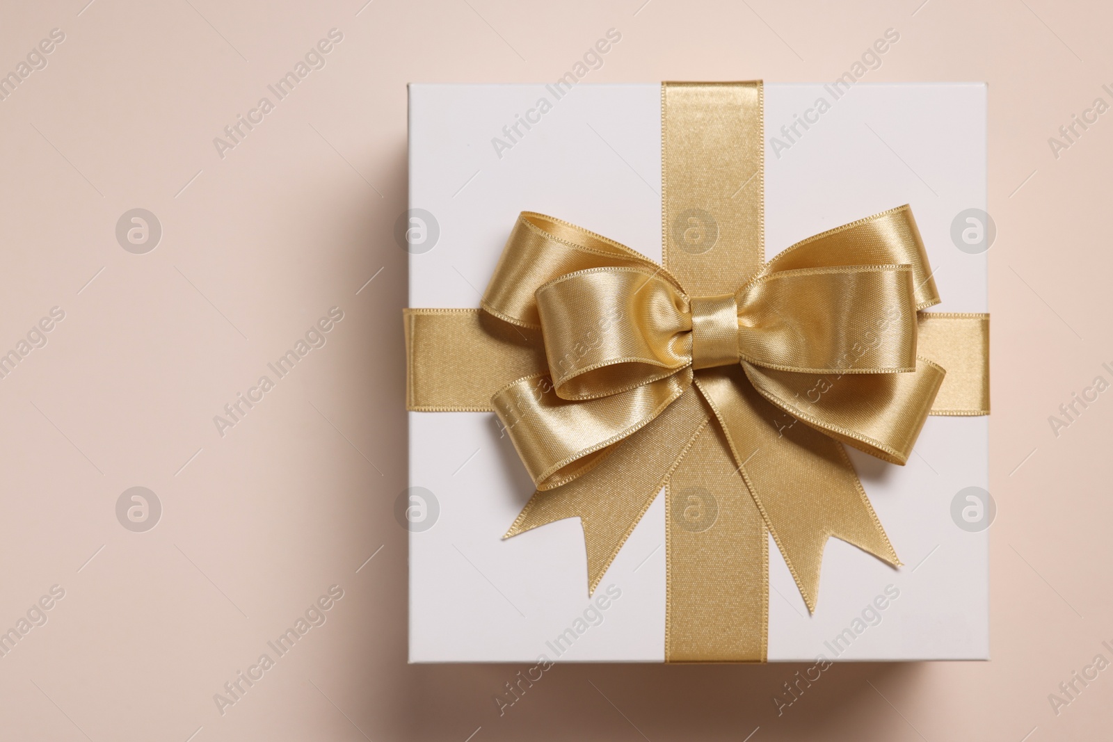 Photo of Gift box with bow on beige background, top view