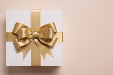 Photo of Gift box with bow on beige background, top view