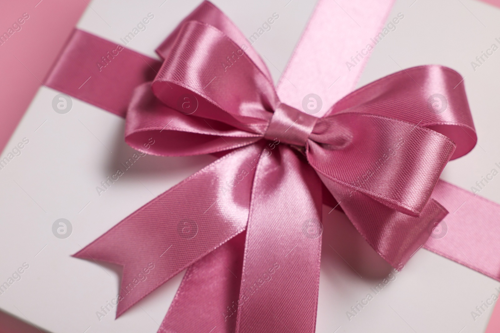 Photo of Gift box with bow on dusty pink background, closeup