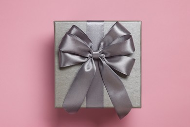 Photo of Gift box with bow on dusty pink background, top view