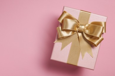 Photo of Gift box with bow on dusty pink background, top view