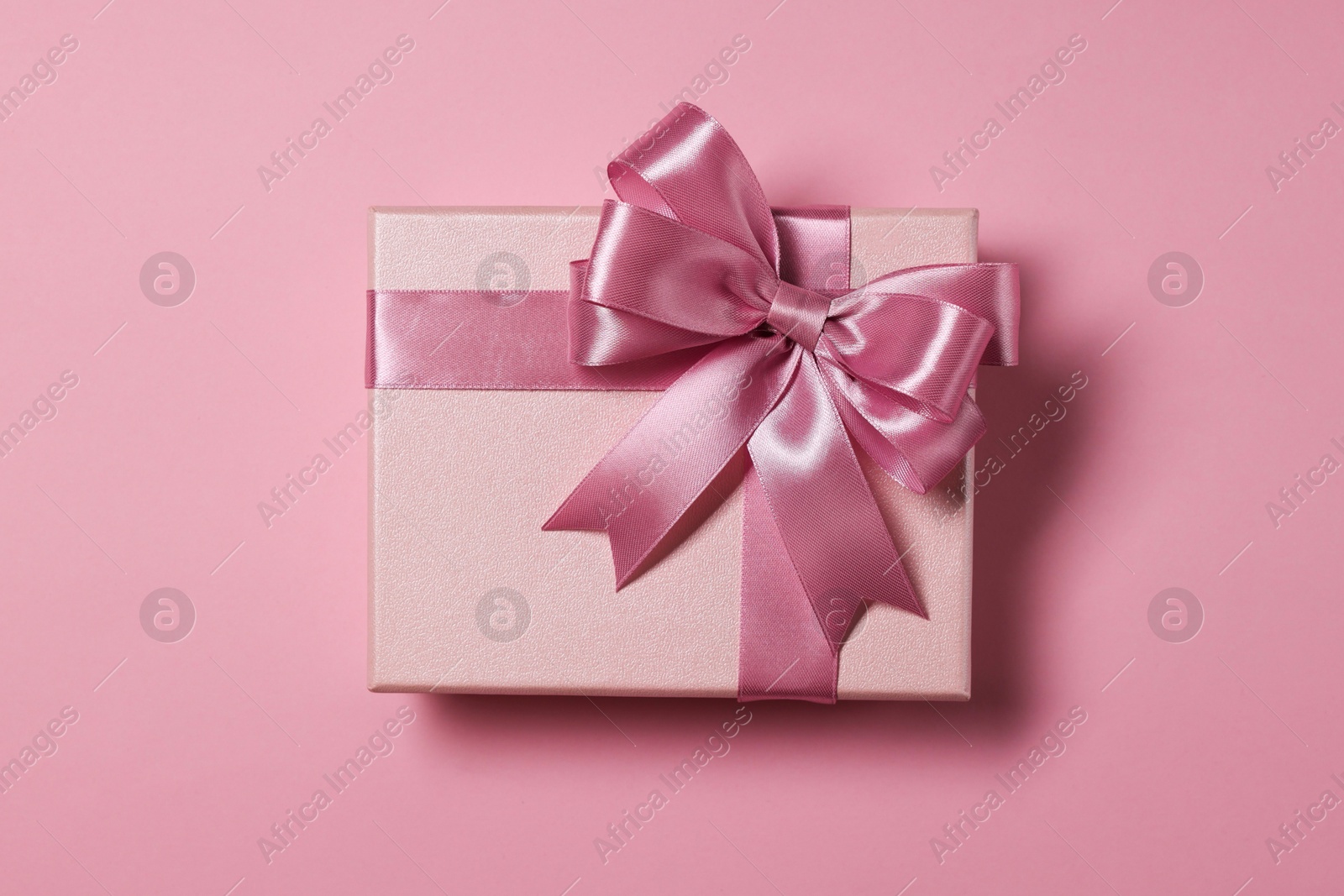 Photo of Gift box with bow on dusty pink background, top view