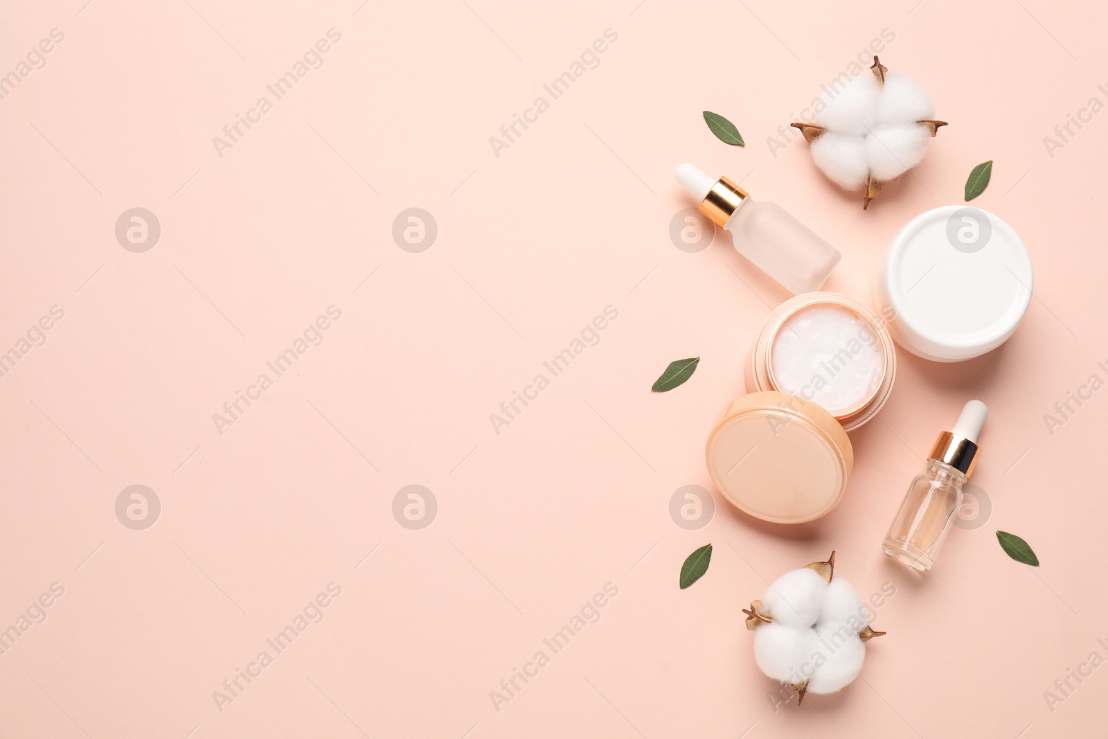 Photo of Different cosmetic products, leaves and cotton flowers on beige background, flat lay. Space for text