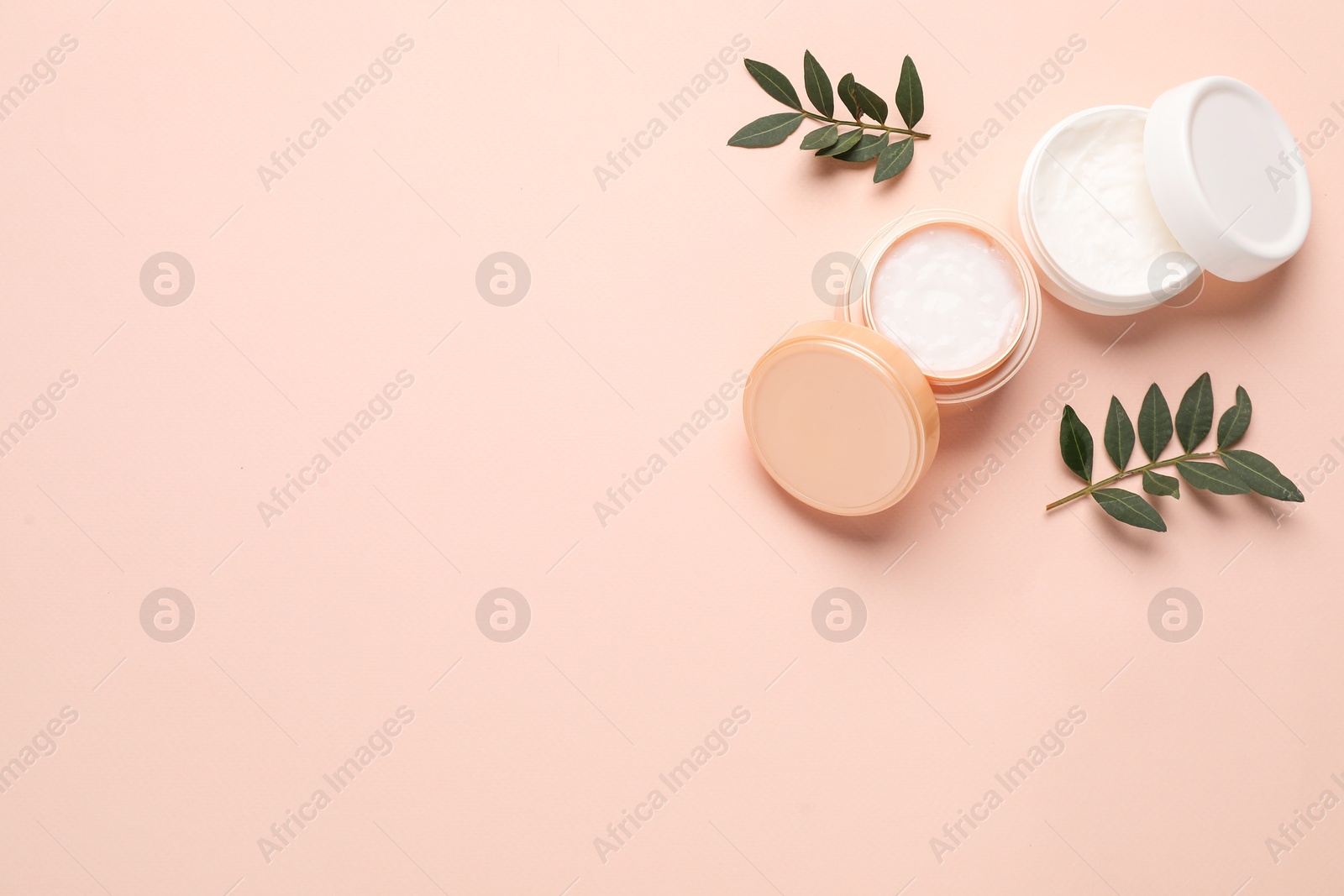 Photo of Different cosmetic products and leaves on beige background, flat lay. Space for text