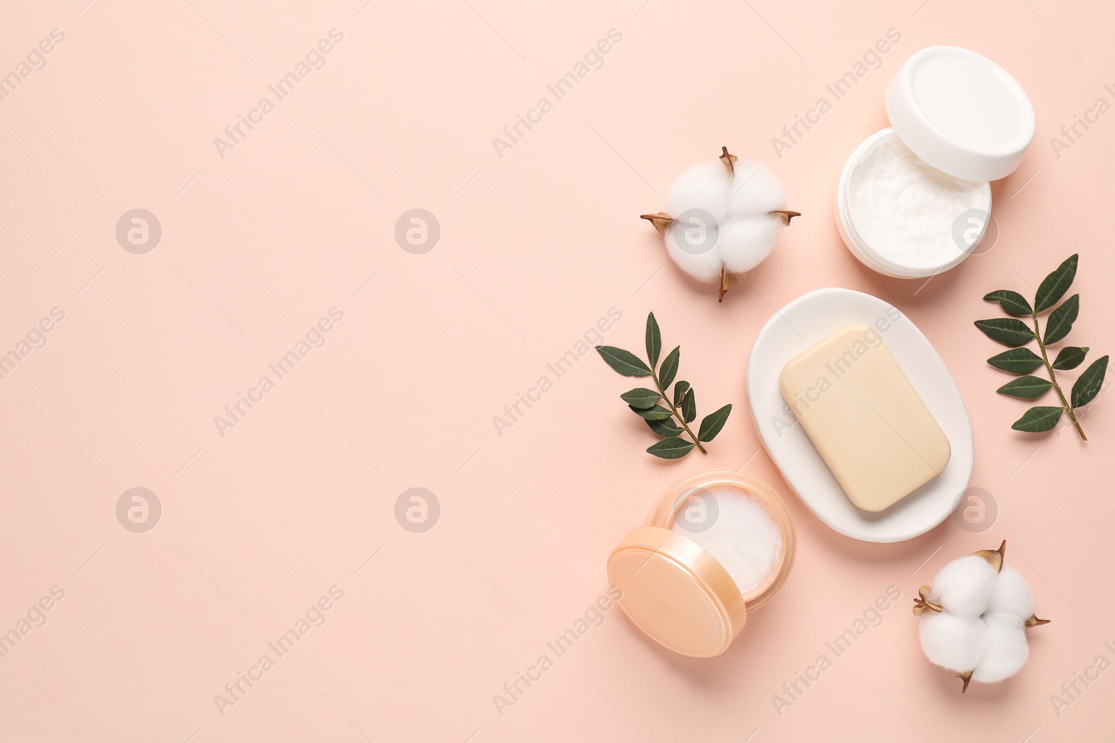 Photo of Different cosmetic products, leaves and cotton flowers on beige background, flat lay. Space for text