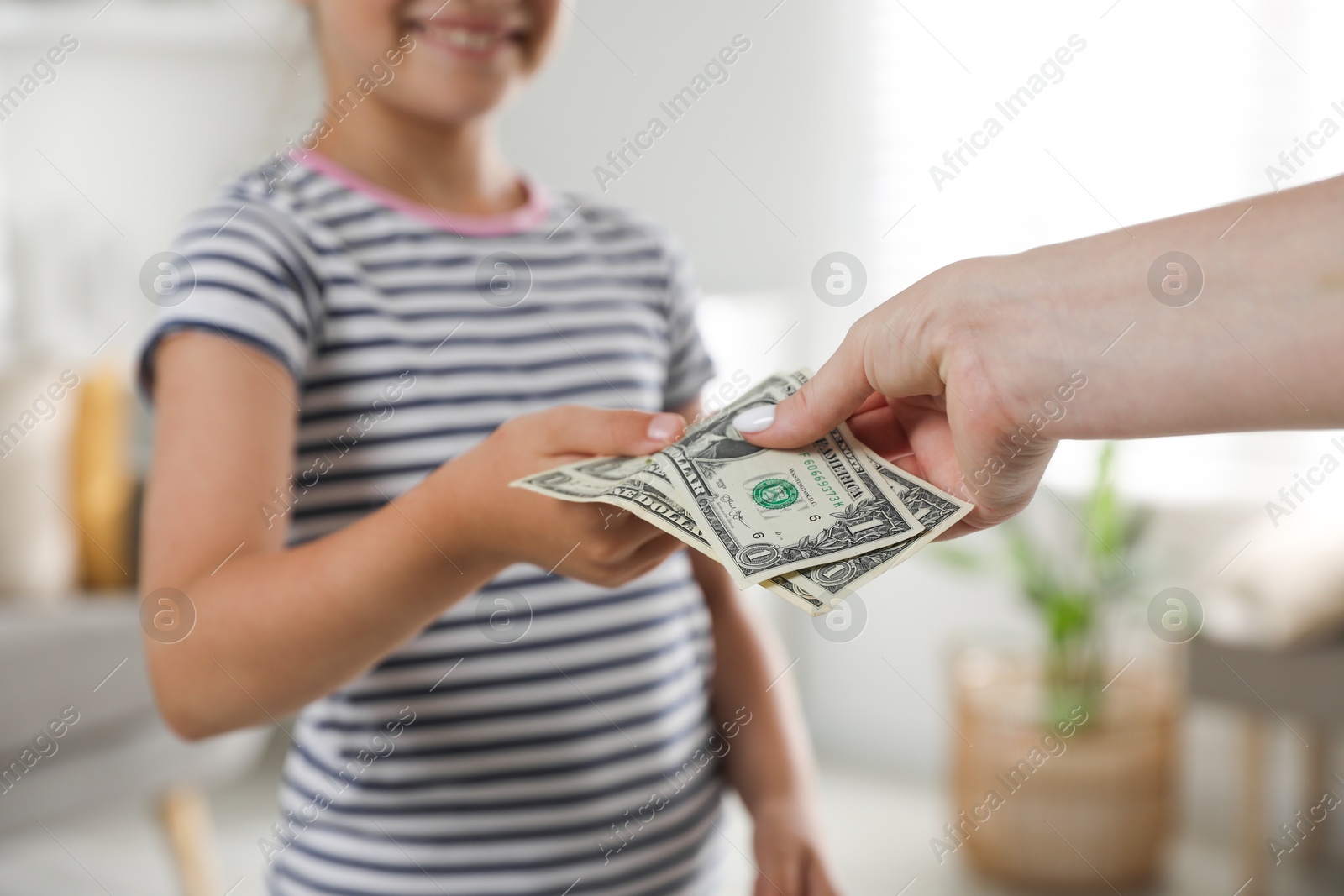 Photo of Mother giving pocket money to her daughter at home, closeup