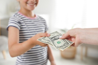 Photo of Mother giving pocket money to her daughter at home, closeup