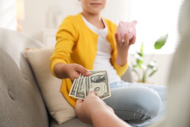 Photo of Mother giving pocket money to her daughter at home, closeup