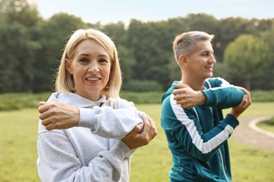 Happy couple doing exercises in park, selective focus