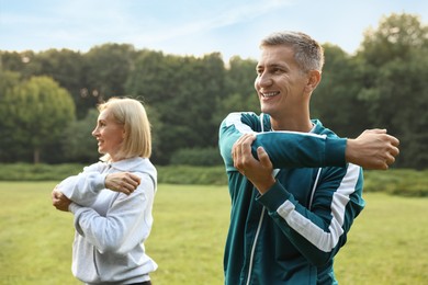 Happy couple doing exercises in park, selective focus