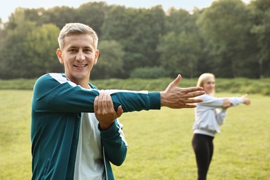 Photo of Happy couple doing exercises in park, selective focus