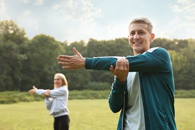 Happy couple doing exercises in park, selective focus