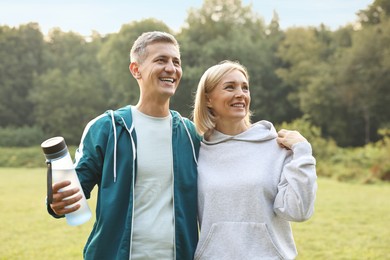 Happy couple with bottle of water in park