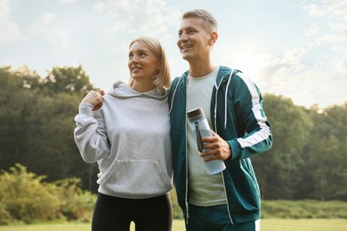 Happy couple with bottle of water in park