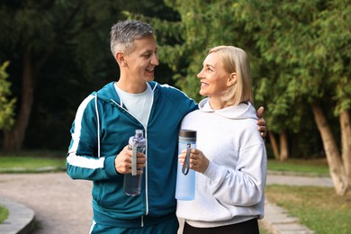 Happy couple with bottles of water in park