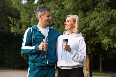 Happy couple with bottles of water in park