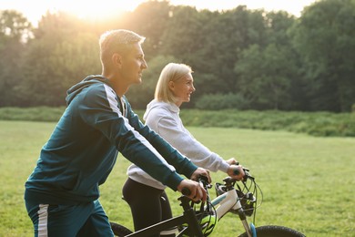 Photo of Happy couple riding bicycles in park. Healthy lifestyle