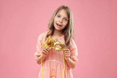 Photo of Cute girl with carnival mask on pink background